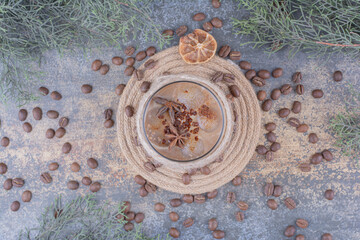 Glass of milk coffee with coffee beans on marble surface