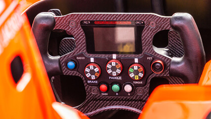 Racing car steering wheel.  Detailed view of an open-wheel single-seater formula racing car. - obrazy, fototapety, plakaty