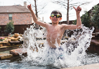 Child wearing swimming goggles in the pool in his backyard