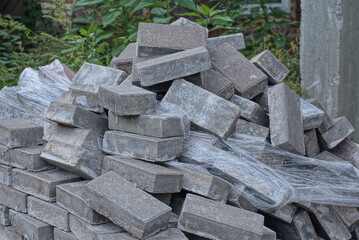 a pile of gray brick paving slabs and white cellophane packaging on the street