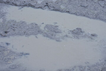 natural texture of gray brown clay and muddy dirty water on the road