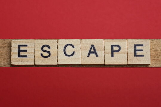 text the word escape from gray wooden small letters with black font on an red table