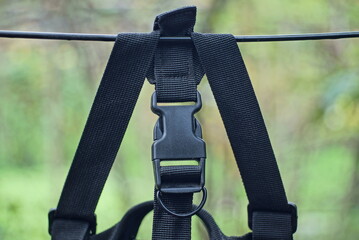 one black plastic carabiner on the harness of a backpack hanging on a wire in the street