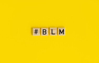 Black Lives Matter Sign. The Word "#BLM" Composed of the Wooden Letters for the Scrabble Game. Black Letters on a Wooden Cubes Arranged on a Yellow Background.