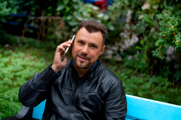 A man of pleasant appearance is talking on the phone. Recreation in the park does not interfere with the solution of business issues.