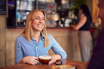 Smiling Couple Sitting At Table In Coffee Shop Together
