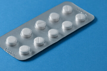 Tablets in a package on a blue background. Medication packaging with soft focus