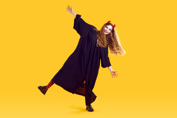 Full length funky funny woman in halloween costumewith terrifying makeup, red devil horns is...