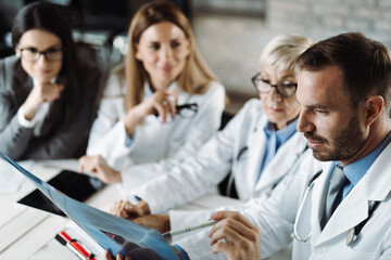 Fototapeta premium Group of doctors analyzing medical scan with businesswoman in the hospital