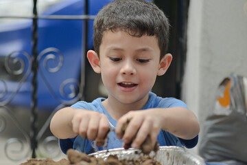 little boy prepares the soil to sow seeds in a urban garden © alejandro