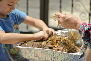 detail of the hands of a grandmother and child fertilizing soil to plant an urban garden © alejandro