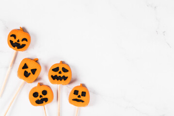 Halloween holiday. Creamy jelly candies in the shape of a pumpkin, on a wooden stick. Light background. Top view. Copy space