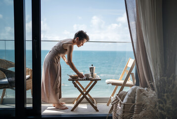 A young woman prepares breakfast on the terrace of her house or hotel in summer. Rest by the sea.