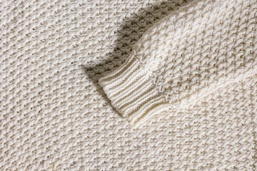 Wool sweater sleeve for winter on beige texture background