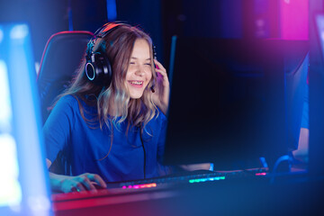 Happy Young caucasian woman pro gamer streamer say in microphone in online video game, neon color...