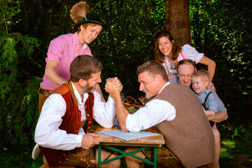 bavarian family sitting outdoors at beer garden having fun - obrazy, fototapety, plakaty