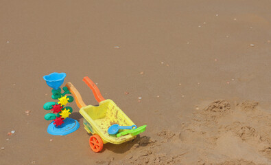 Bright children's toys on the wet sand with shells