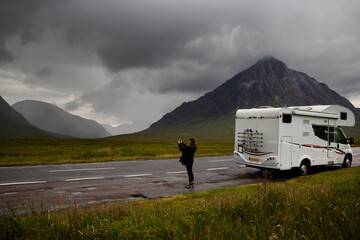 A tourist in a motorhome takes pictures with her mobile phone of Glen Etive in Glen Coe, Scotland - obrazy, fototapety, plakaty