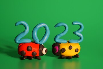 Two ladybugs and the number 2023 on a green background. A festive event. New Year and Christmas.