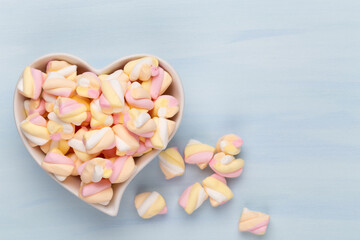 Marshmallows on blue background with copyspace. Flat lay or top view. Background or texture of colorful mini marshmallows.