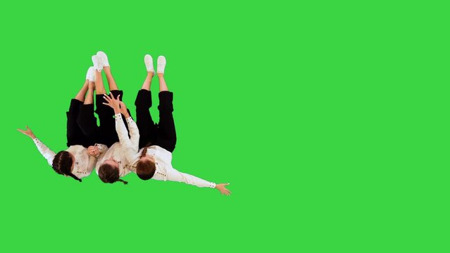 A group of carefree ladies in white shirts and black capri pants have fun riding a skateboard all together on a Green Screen, Chroma Key.