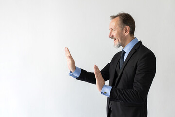 Portrait of stressed mature businessman making stop gesture. Terrified senior Caucasian manager wearing three piece suit protecting himself from problems. Fear and problems concept