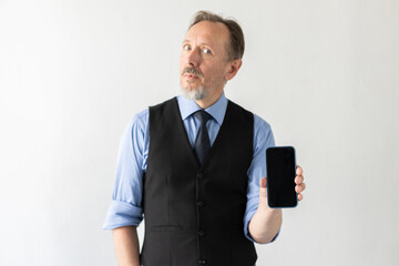 Portrait of confident mature businessman showing smartphone against white background. Senior Caucasian manager wearing formalwear holding mobile phone. Mobile technology concept