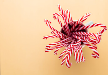 Christmas candy canes in a cup, pastel background.