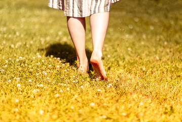 Bare girls feet walking, going away on grass on summer holiday closeup