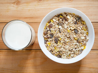 A Bowl of muesli breakfast and rolled oats with dried fruits and a glass of milk