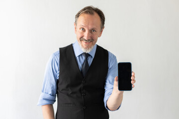 Portrait of happy mature businessman showing smartphone against white background. Senior Caucasian manager wearing formalwear holding mobile phone and smiling. Mobile technology concept