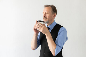 Portrait of delighted mature businessman drinking coffee. Senior Caucasian manager wearing formalwear enjoying takeout drink against white background. Coffee break concept