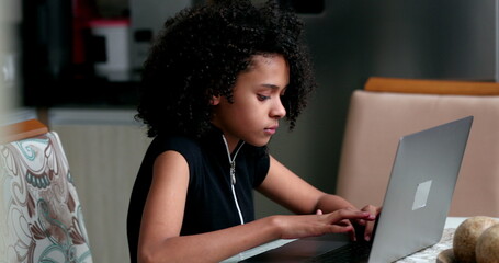 Candid black teen girl using laptop computer studying