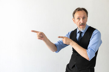 Portrait of surprised mature businessman pointing finger at something. Senior Caucasian manager wearing formalwear looking at camera and showing direction against white background. Advertising concept
