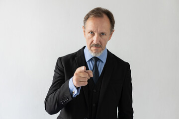 Portrait of confident mature businessman pointing at camera. Senior Caucasian man wearing three piece suit looking at camera in suspicion. Employment or blame concept