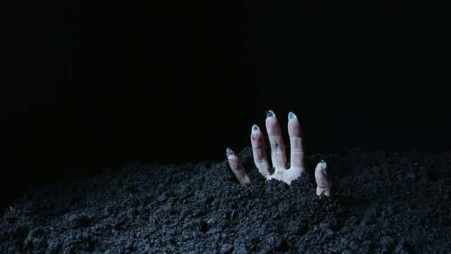 A terrible hand with claws emerges from the ground. Halloween background.