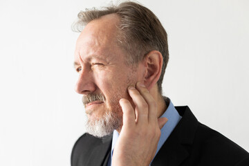 Close-up of frowning mature businessman touching his cheek. Portrait of senior Caucasian manager...