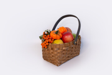 wicker basket full of fruit vegetables berries on a white background, thanksgiving day, autumn, harvest, gardening, farming, pumpkin, apples, rowan, orange, halloween, seasonal holiday, space for text