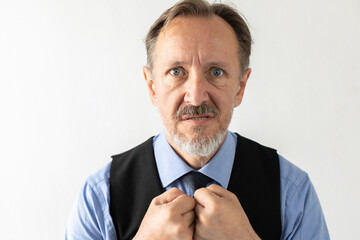 Portrait of grumpy mature businessman looking at camera. Senior Caucasian manager wearing formalwear clenching fists and grumbling against white background. Irritation concept