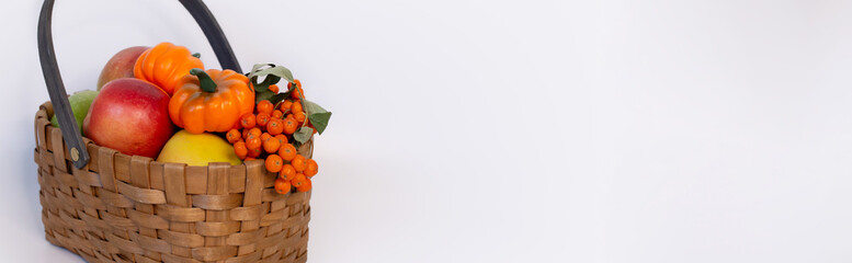 wicker basket full of fruit vegetables berries on a white background, thanksgiving day, autumn, harvest, gardening, farming, pumpkin, apples, rowan, orange, halloween, seasonal holiday, space for text