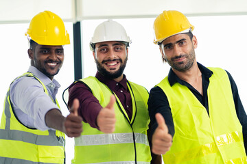 A group of expert engineers and workers giving thumbs up in the construction site office. Diverse teamwork is successful at work