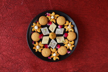 Diwali Diya on red background, Sweets OR Mithai in indian thali  arranged over decorative background. Selective focus, Indian festival