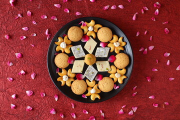 Diwali Diya on red background, Sweets OR Mithai in indian thali  arranged over decorative background. Selective focus, Indian festival