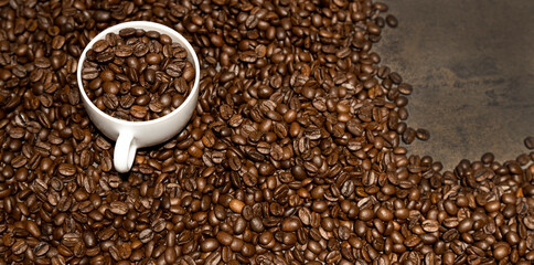 Spilled coffee beans, a cup of coffee and coffee beans on the table.
