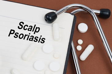 On a brown surface lies a stethoscope, pills and a notepad with the inscription - Scalp Psoriasis