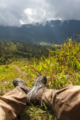 Dirty hiking boots and gaiters of tourist having a rest and watching the Baliem Valley, after a...