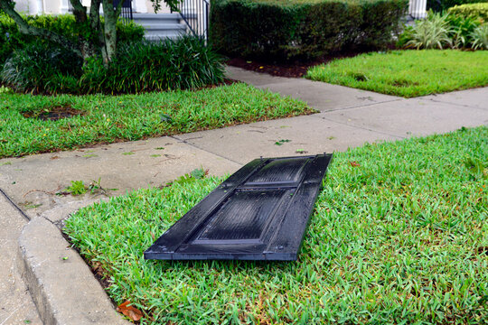 Fallen, Black Shutter On Wet, Green Lawn In Front Of A Townhouse Entrance Following Hurricane Ian Passing Through Orlando