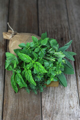 Fresh herb bouquet with rosemary, thyme, mint, sage and different kind of basil. Farm-to market herbs and sprigs tied with string in a bouquet on wooden background.