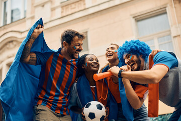 Group of cheerful soccer fans celebrate their favorite team's victory on street.