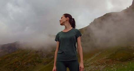 Woman standing in mountain, enjoying breathtaking view. Medium shot